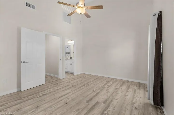 Unfurnished room with light wood-type flooring, a ceiling fan, and a high ceiling
