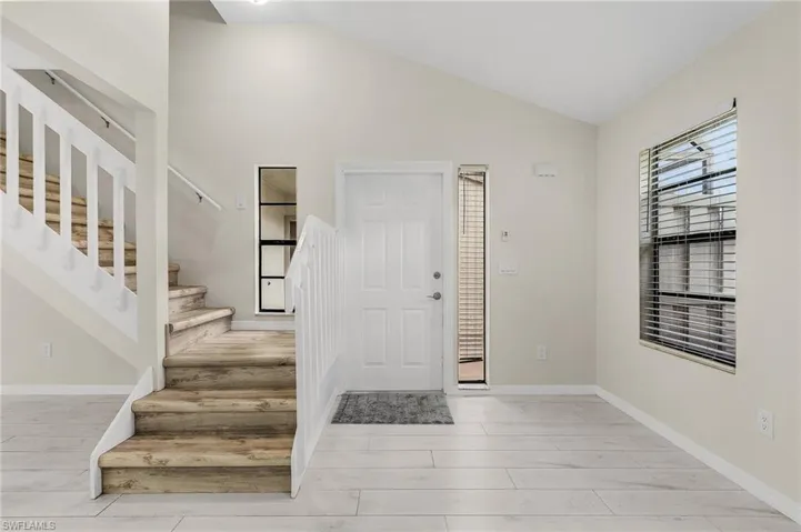 Entrance foyer with stairway, vaulted ceiling, and light wood finished floors