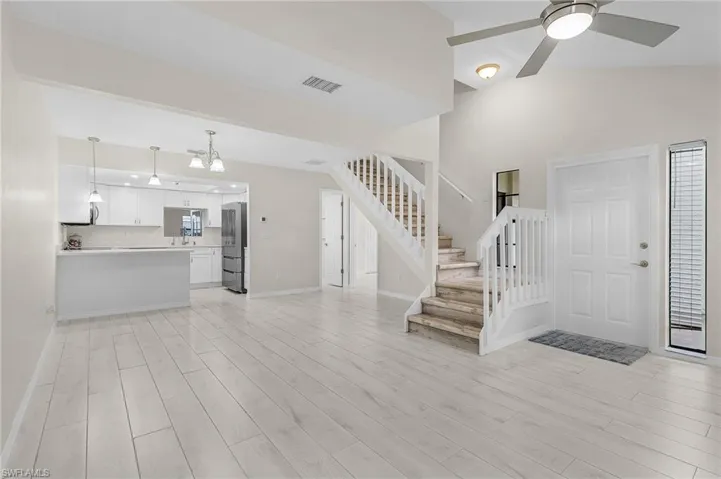 Foyer with light wood-style floors, stairway, and ceiling fan