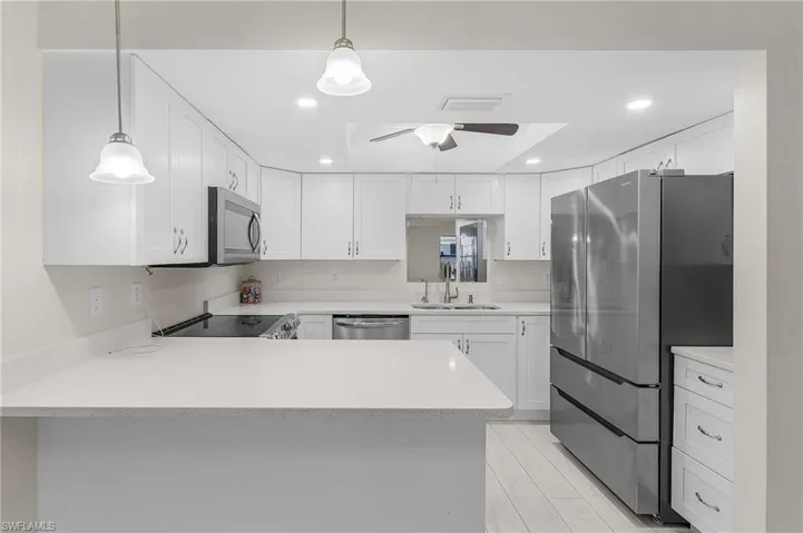 Kitchen featuring appliances with stainless steel finishes, a ceiling fan, white cabinets, a peninsula, and recessed lighting