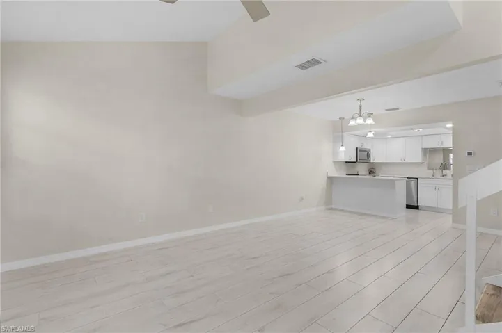Unfurnished living room with a chandelier and light wood-style flooring