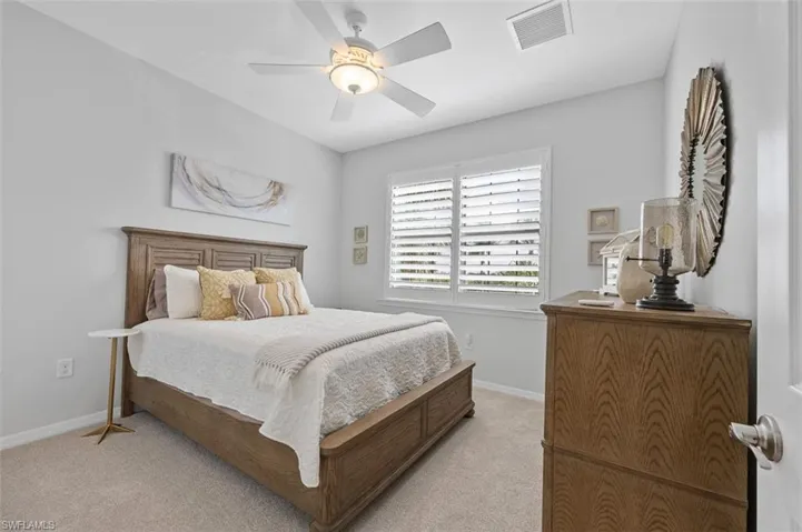 Bedroom with baseboards, ceiling fan, visible vents, and light colored carpet