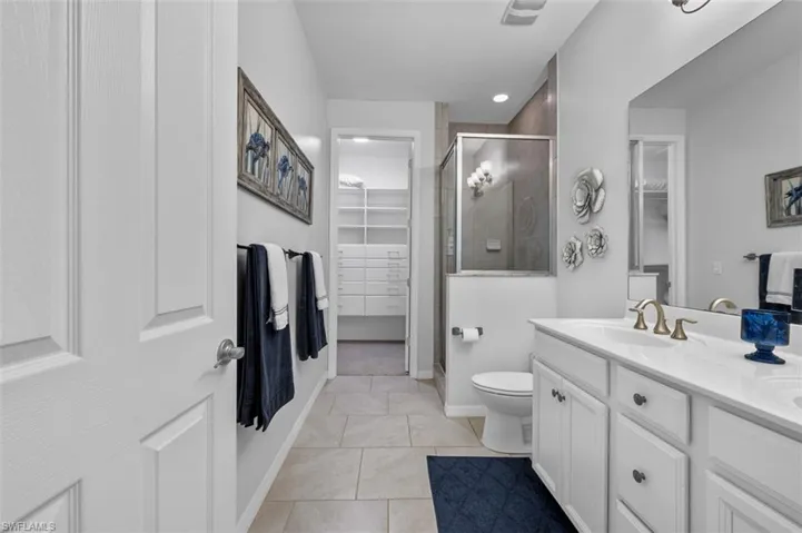 Bathroom with tile patterned flooring, vanity, a walk in closet, toilet, and a shower stall