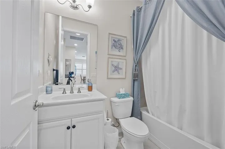 Full bathroom with visible vents, toilet, vanity, and shower / bathtub combination with curtain