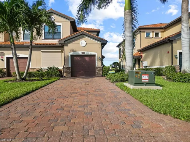 View of front of house featuring a tile roof, stucco siding, an attached garage, stone siding, and decorative driveway