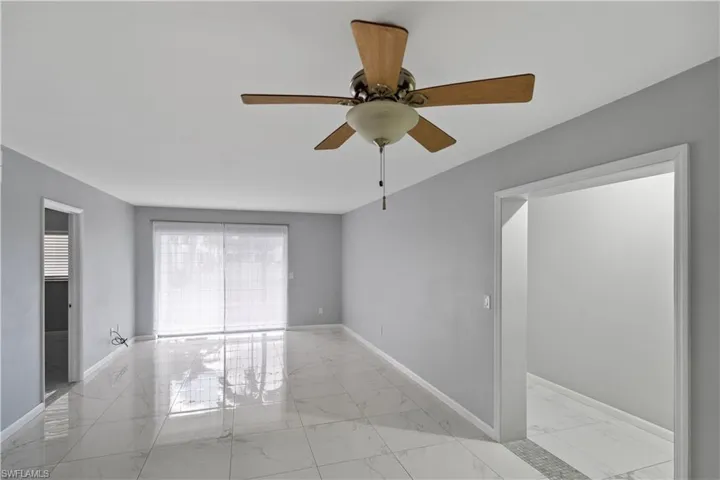 Unfurnished room featuring light marble finish flooring and a ceiling fan