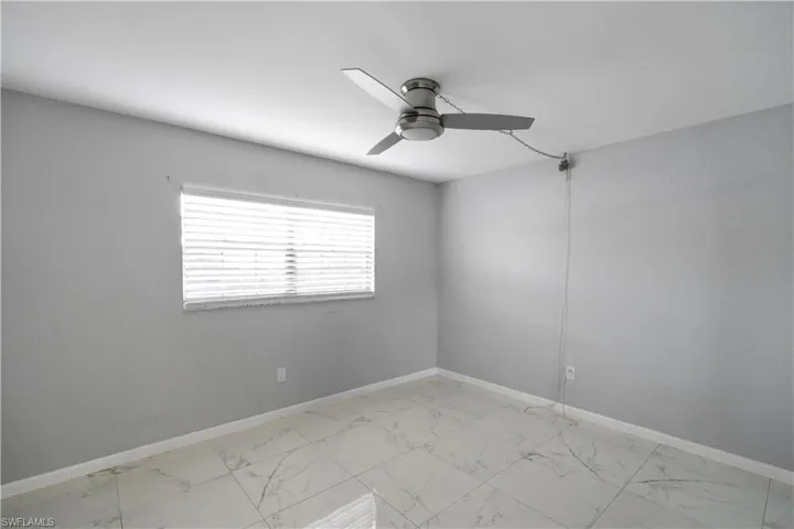 Unfurnished room with light marble finish flooring and a ceiling fan