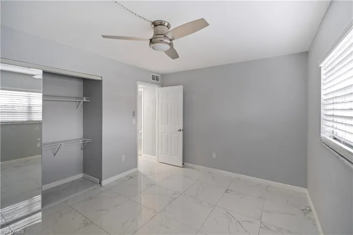 Unfurnished bedroom with light marble finish flooring, a ceiling fan, and a closet