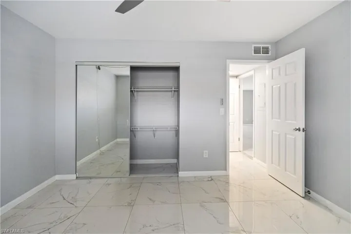 Unfurnished bedroom featuring light marble finish floors, a closet, and ceiling fan