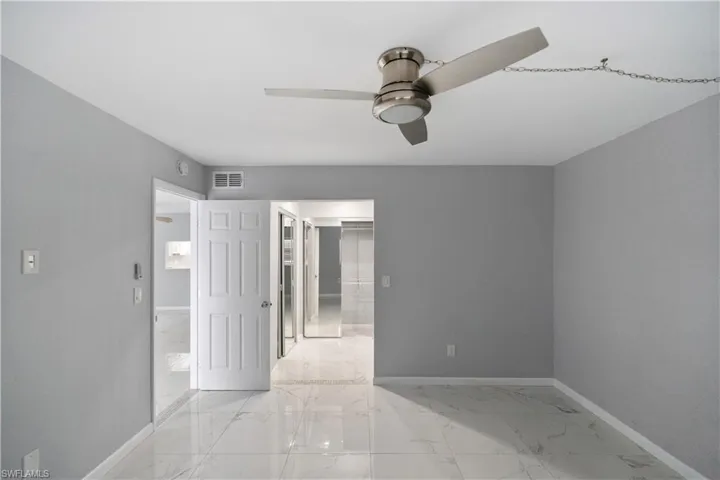 Unfurnished bedroom featuring light marble finish flooring, a ceiling fan, and a spacious closet
