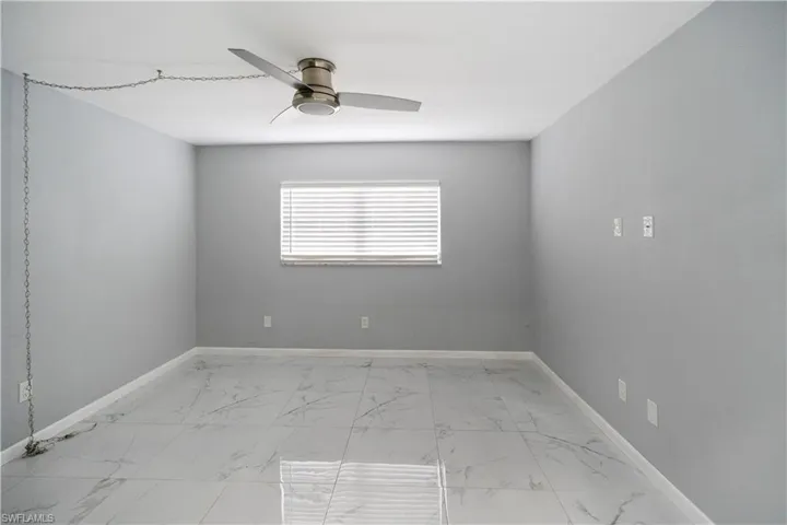 Unfurnished room with light marble finish floors and ceiling fan