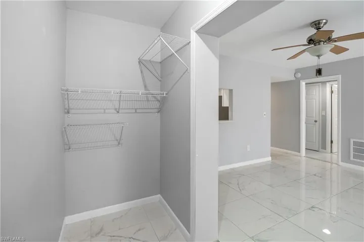 Spacious closet featuring light marble finish flooring and a ceiling fan