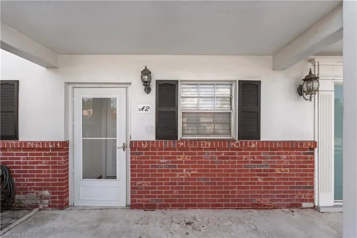 View of exterior entry featuring covered porch, stucco siding, and brick siding