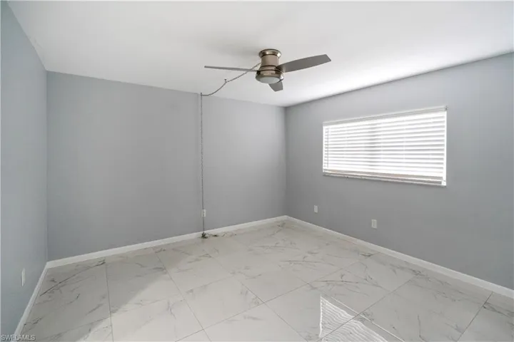 Unfurnished room featuring light marble finish floors and a ceiling fan