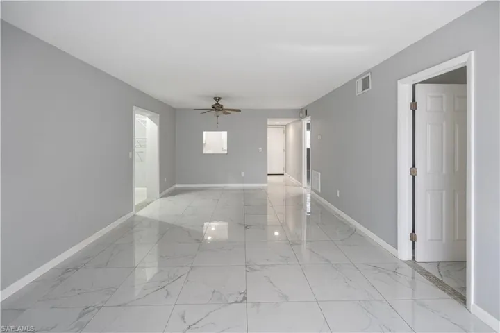 Unfurnished room with light marble finish floors and a ceiling fan
