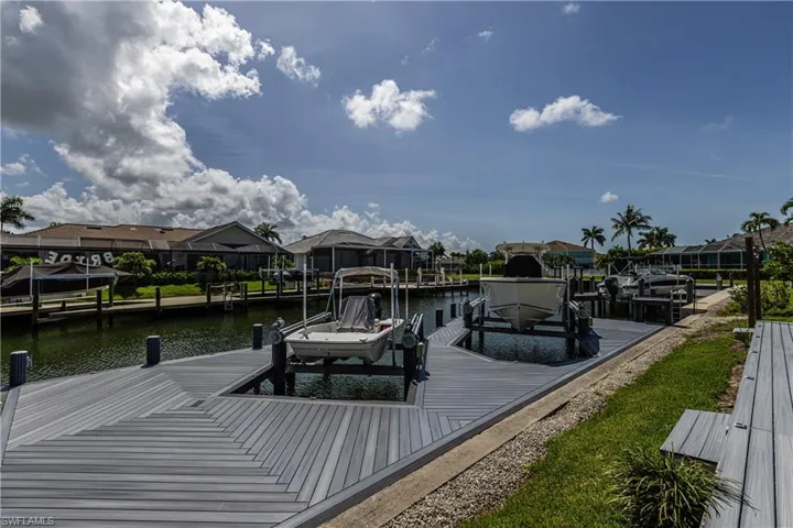 Dock featuring boat lift, a water view, and a residential view