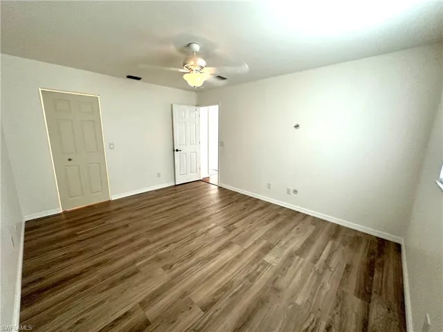 Unfurnished bedroom with wood finished floors, ceiling fan, baseboards, and visible vents
