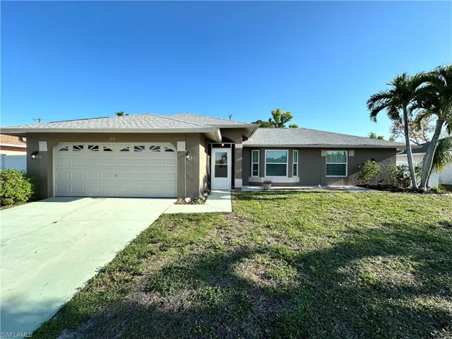 Ranch-style home with a garage, stucco siding, concrete driveway, and a front lawn