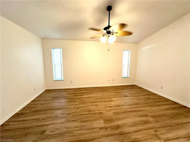 Unfurnished room with ceiling fan, wood finished floors, and baseboards