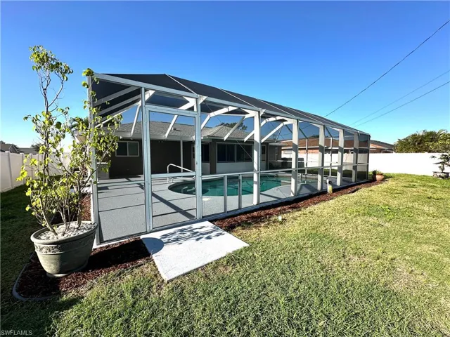 View of swimming pool featuring a patio area, a lawn, a fenced backyard, glass enclosure, and a fenced in pool