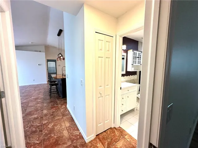 Hallway with baseboards and lofted ceiling