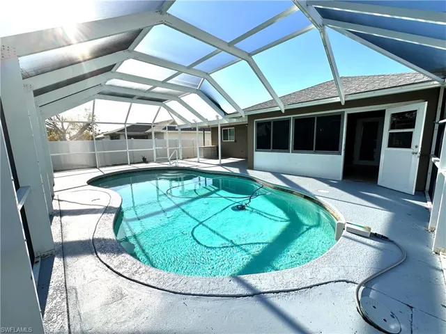 View of pool featuring fence, a fenced in pool, a patio, and glass enclosure