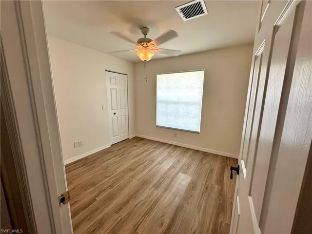 Unfurnished bedroom with light wood finished floors, visible vents, baseboards, and a ceiling fan
