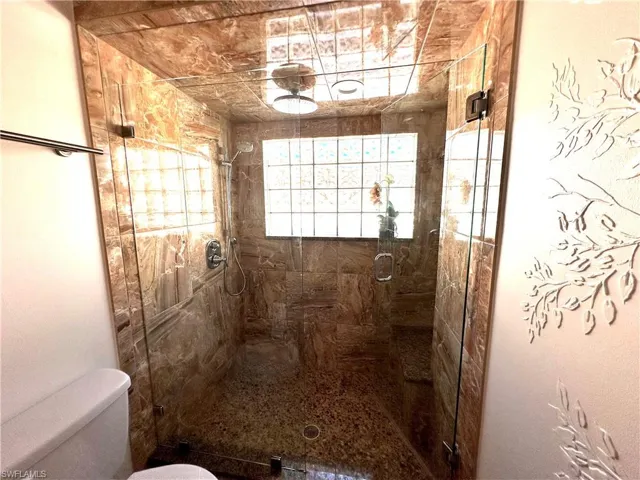 Full bathroom with toilet and a shower stall