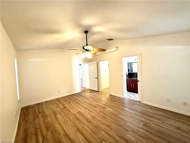 Unfurnished living room featuring visible vents, baseboards, a ceiling fan, and wood finished floors