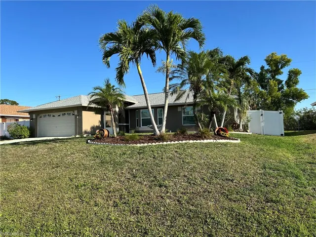 Ranch-style house with stucco siding, driveway, a front lawn, a garage, and fence