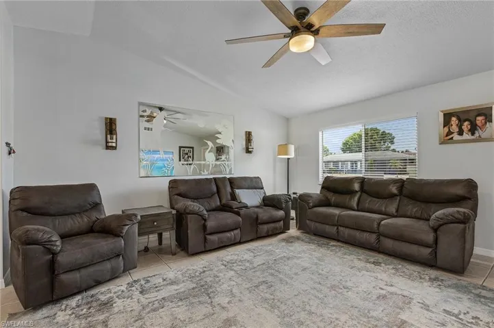 Living room with tile flooring, ceiling fan, and lofted ceiling