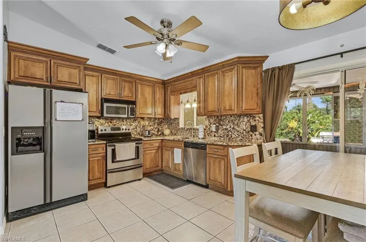 Kitchen with ceiling fan, tasteful backsplash, stainless steel appliances, light tile floors, and sink
