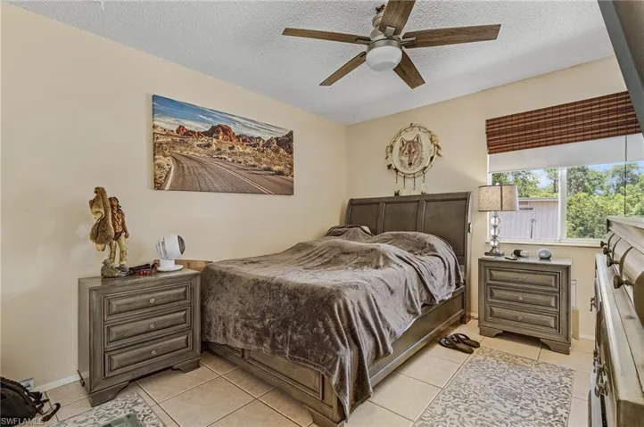 Tiled bedroom with ceiling fan and a textured ceiling