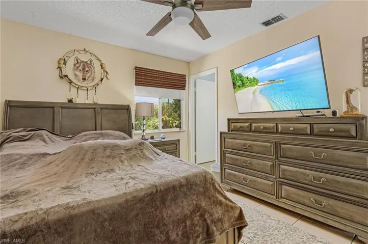 Tiled bedroom with ceiling fan and a textured ceiling