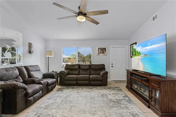 Tiled living room with ceiling fan and lofted ceiling
