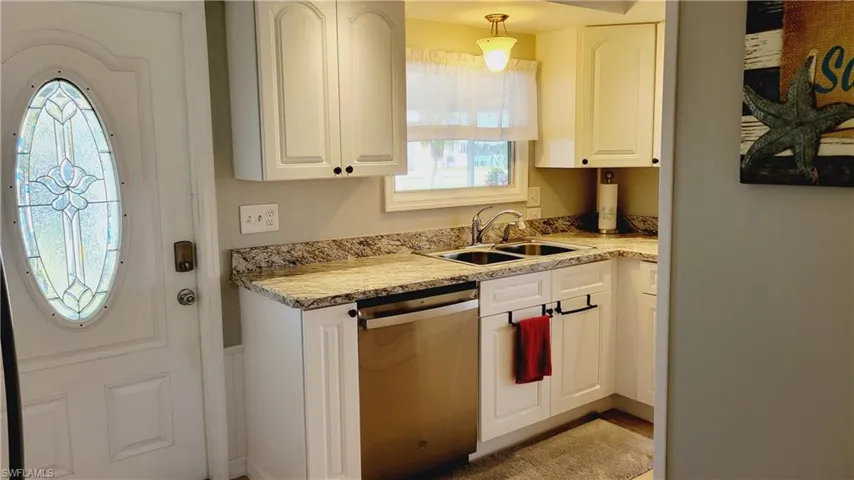 Kitchen with dishwasher, light stone countertops, decorative light fixtures, and white cabinets