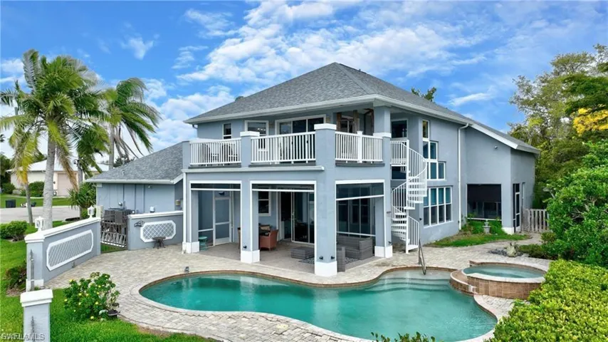Rear view of house featuring a patio area, a balcony, a shingled roof, a pool with connected hot tub, and stucco siding