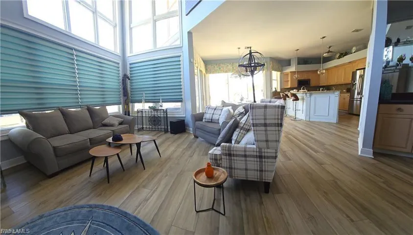 Living area with light wood finished floors, a high ceiling, and hanging lights