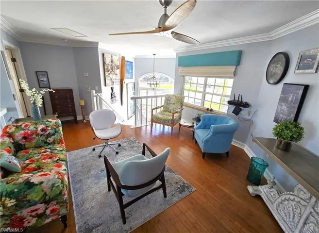 Living room with ceiling fan, crown molding, hardwood / wood-style floors, and hanging lights