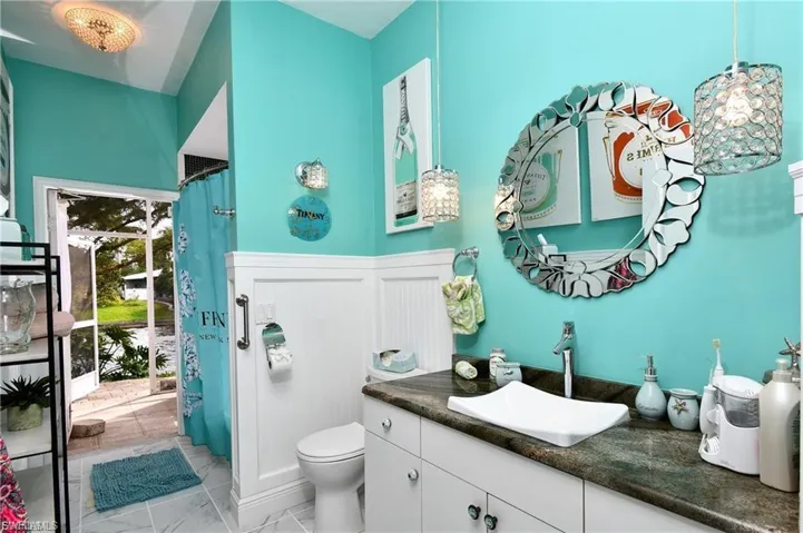 Bathroom with a shower with shower curtain, vanity, and wainscoting
