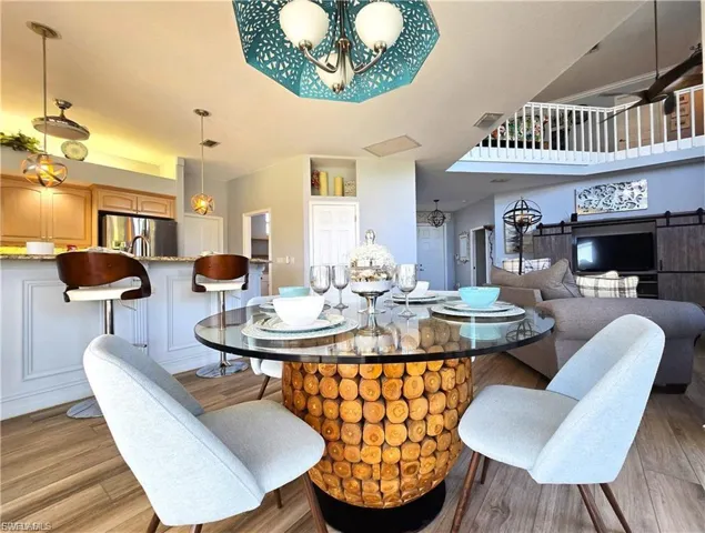 Dining space with light wood-style floors, a barn door, and suspended lighting