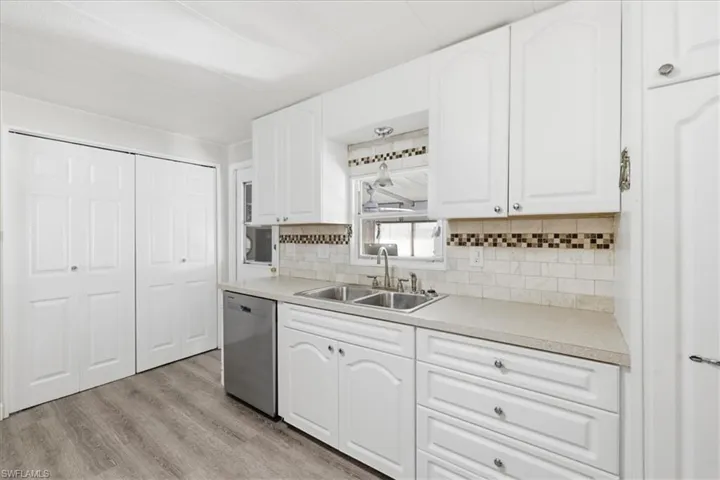 Kitchen with light countertops, white cabinets, dishwasher, tasteful backsplash, and light wood-style flooring