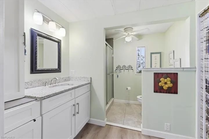 Full master bathroom with vanity, a stall shower, ceiling fan, and light wood finished floors