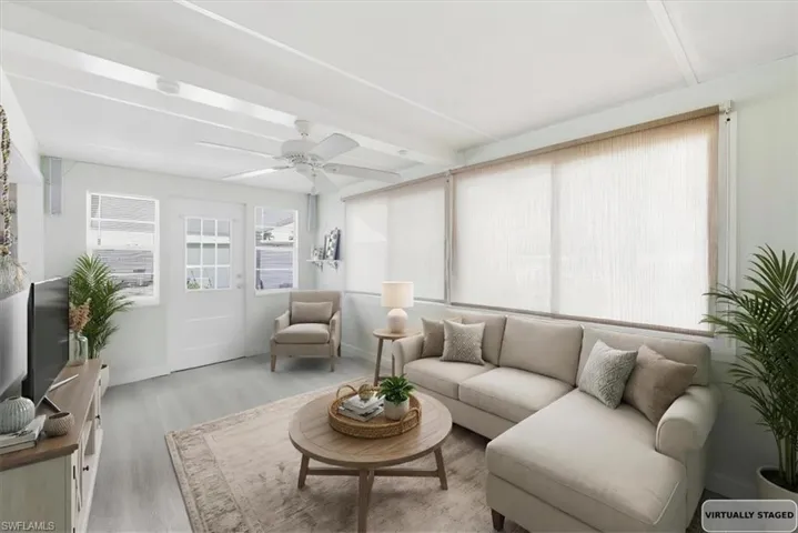 Living area with wood finished floors and a ceiling fan virtually staged