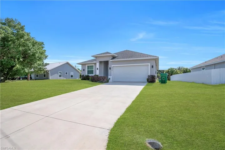Single-story residence featuring a two-car garage, concrete driveway, and a well-maintained lawn