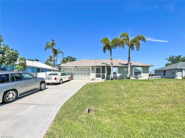 Single story home with a garage and a front lawn