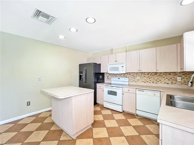 Kitchen featuring sink, white appliances, light tile flooring, and tasteful backsplash