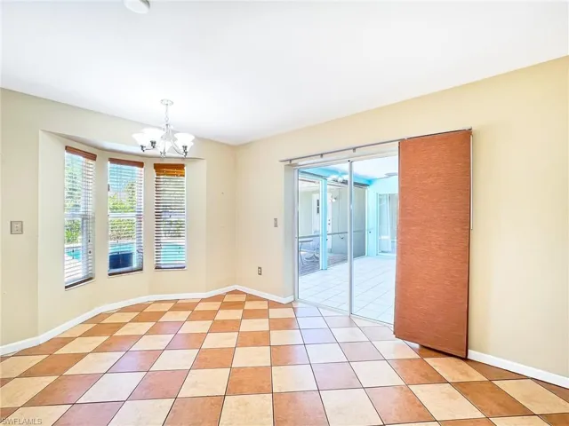 Tiled spare room featuring a chandelier