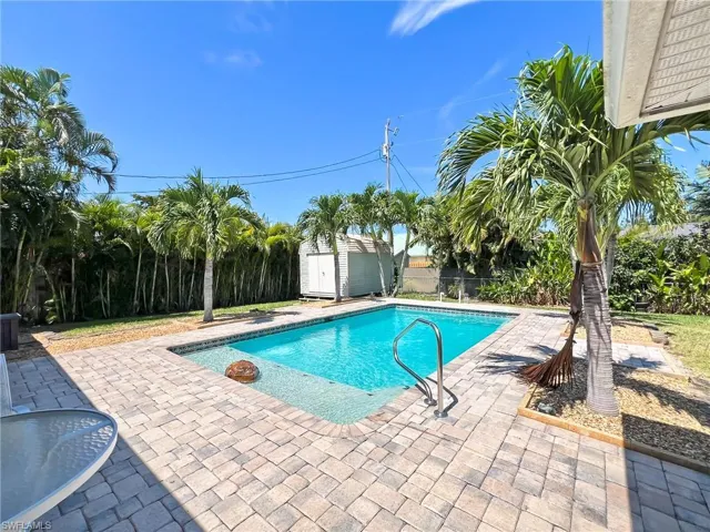 View of pool with a patio and a shed