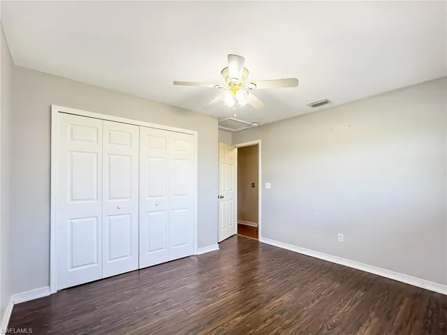 Unfurnished bedroom with a closet, ceiling fan, and dark hardwood / wood-style flooring